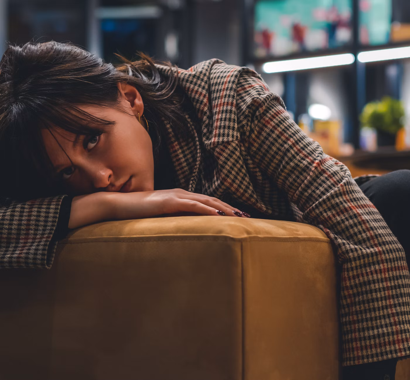Femme pensive, la tête appuyée sur la main, sur un canapé
