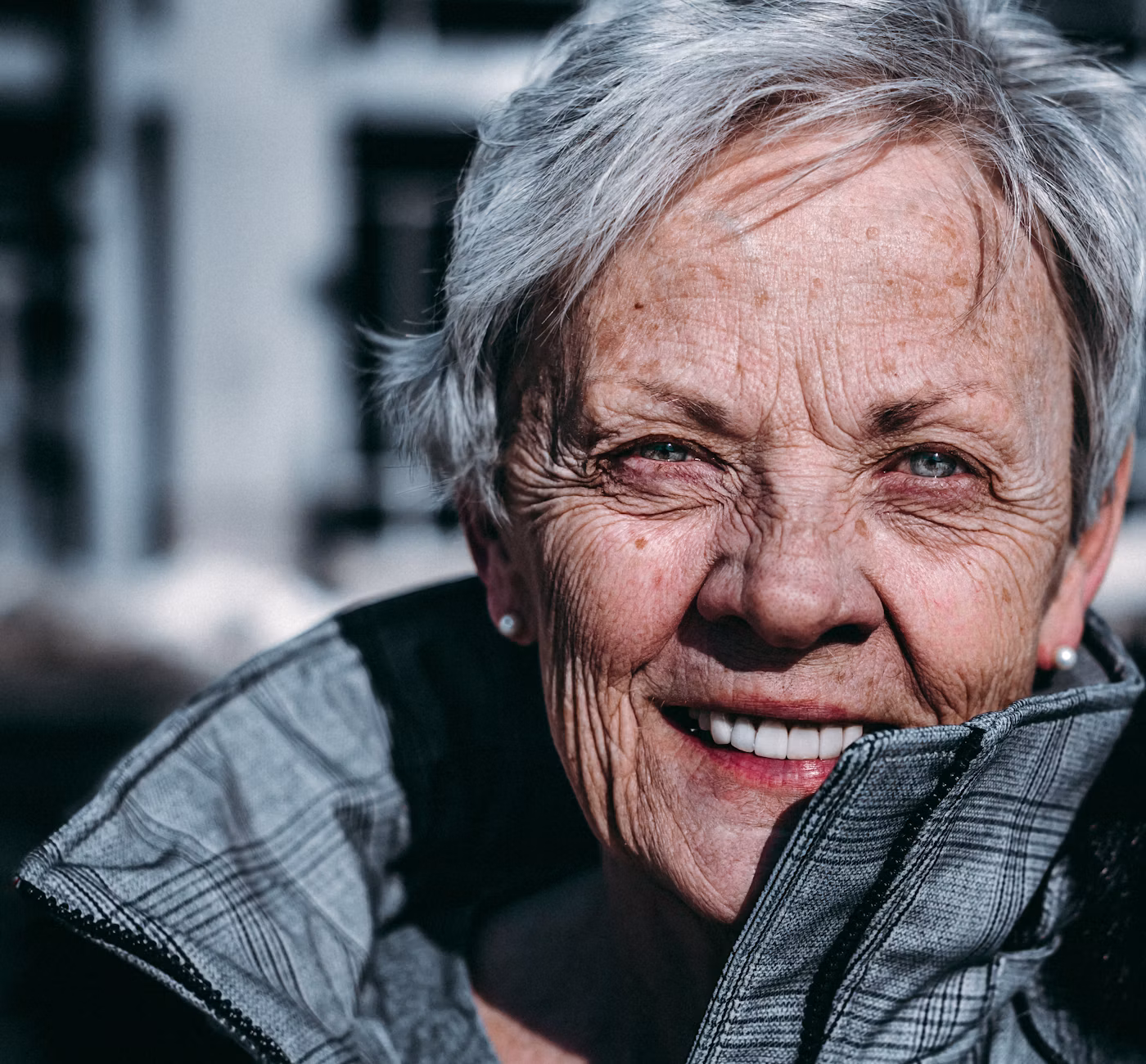 Femme aux cheveux gris, souriante, portant des lunettes
