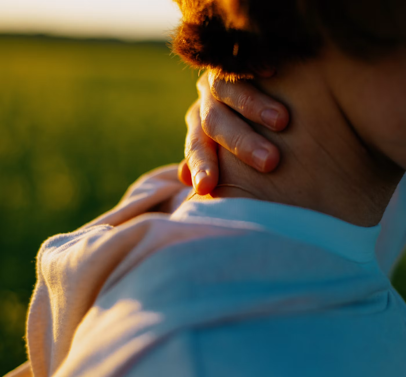 Femme les mains posées sur le cou, dans un champ