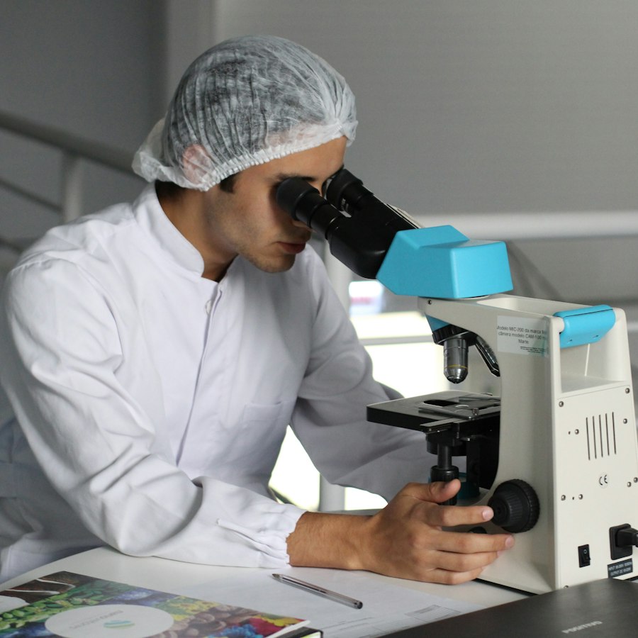 Biologiste au microscope, en blouse et charlotte