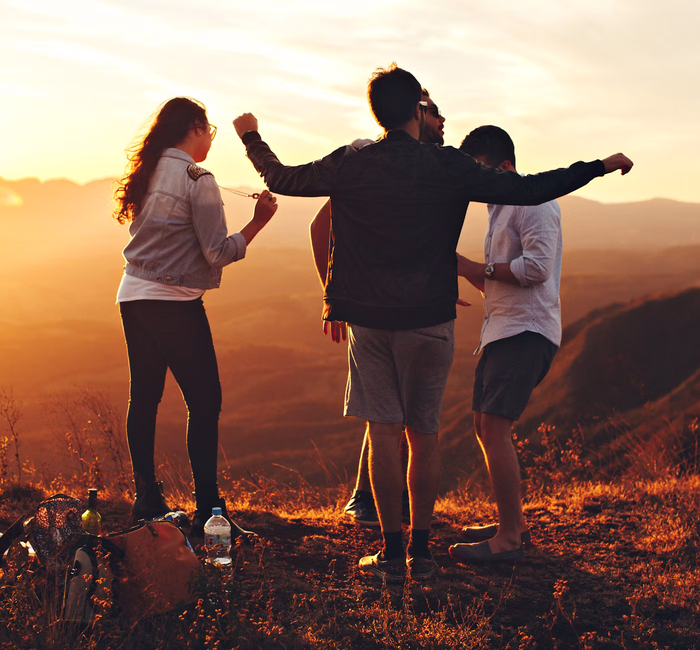 Quatre amis au sommet d'une colline au coucher du soleil